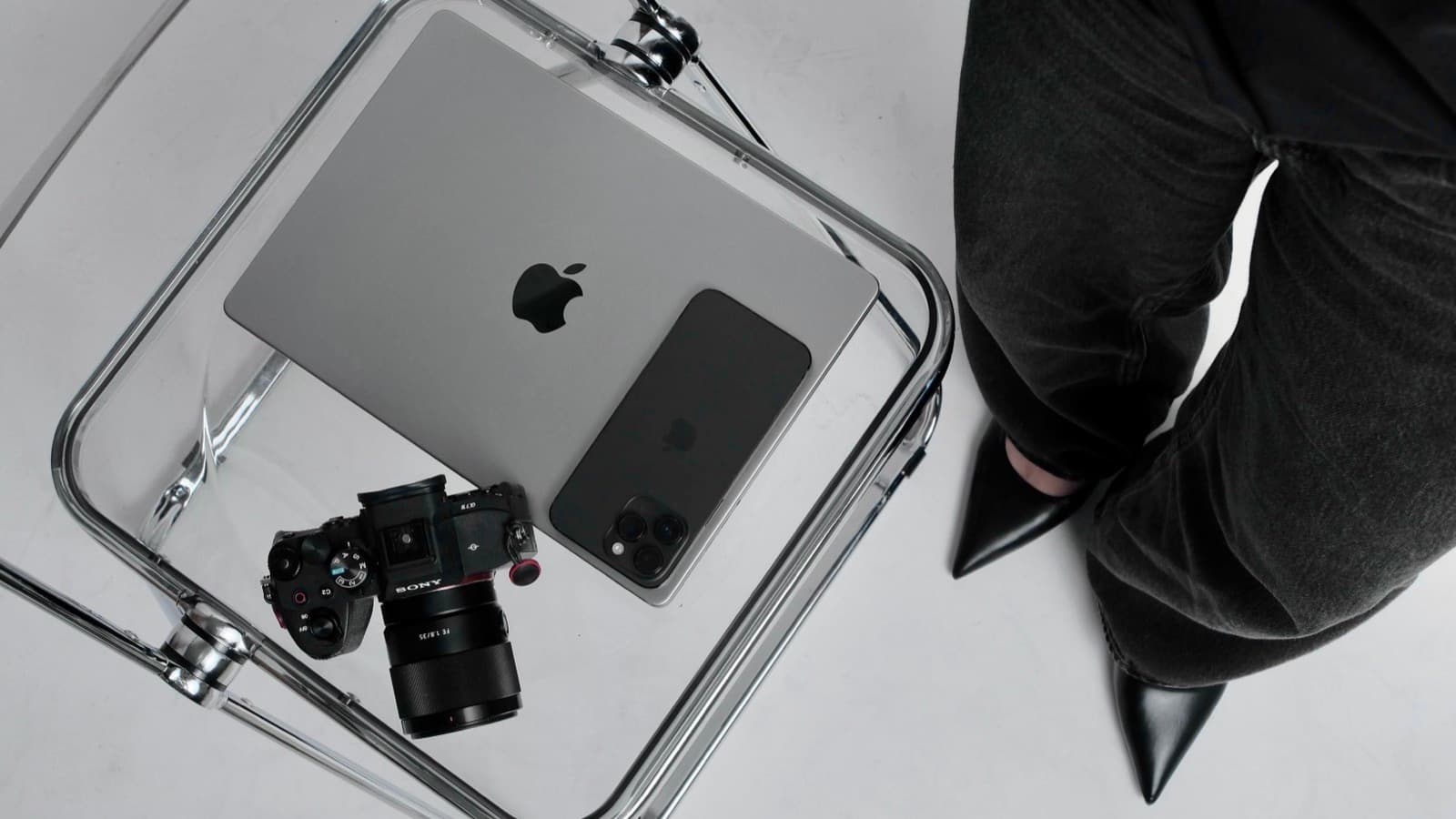 Overhead shot of a laptop, smartphone and camera on a glass table, representing a creator's original work