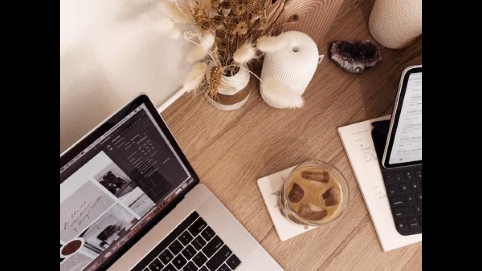A notebook with pricing calculations beside a laptop and smartphone