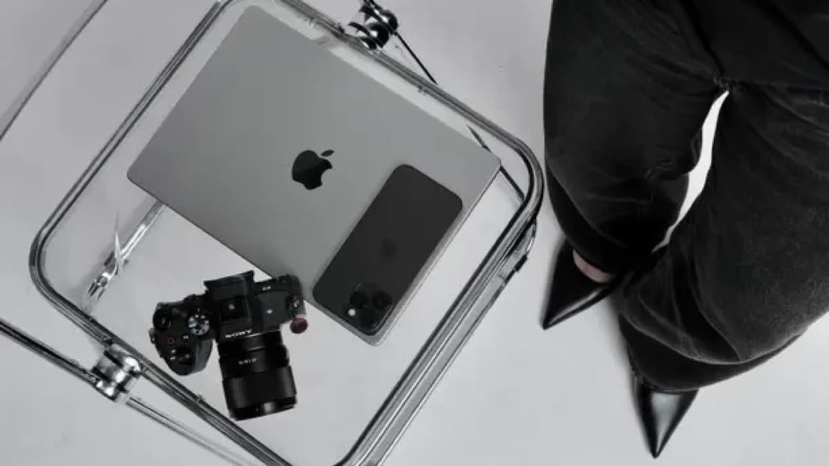 Camera, laptop, and phone arranged on a clear table